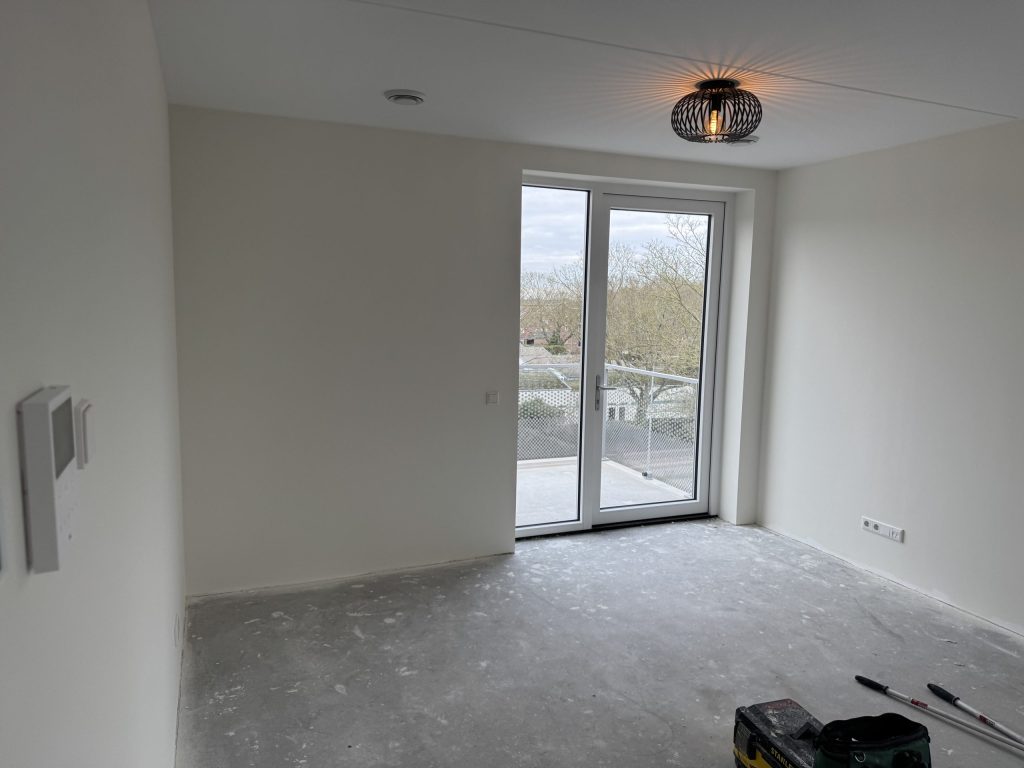 Kale appartementskamer met openslaande deuren naar een balkon